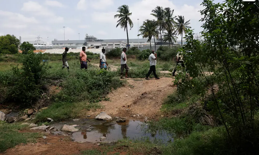 Farmers walk alongside Indian officials surveying the farmlands surrounding the Tata Electronics components factory for Apple's iPhone in Hosur, Tamil Nadu, India, June 15, 2026. REUTERS