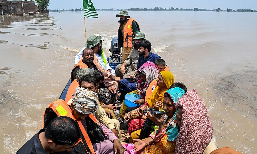 People sitting on a rescue boat ride through a flooded area after heavy monsoon rains induced a rise in the water level of the River Ravi in Pakistan's Muridke on July 27, 2026. Photo: AFP