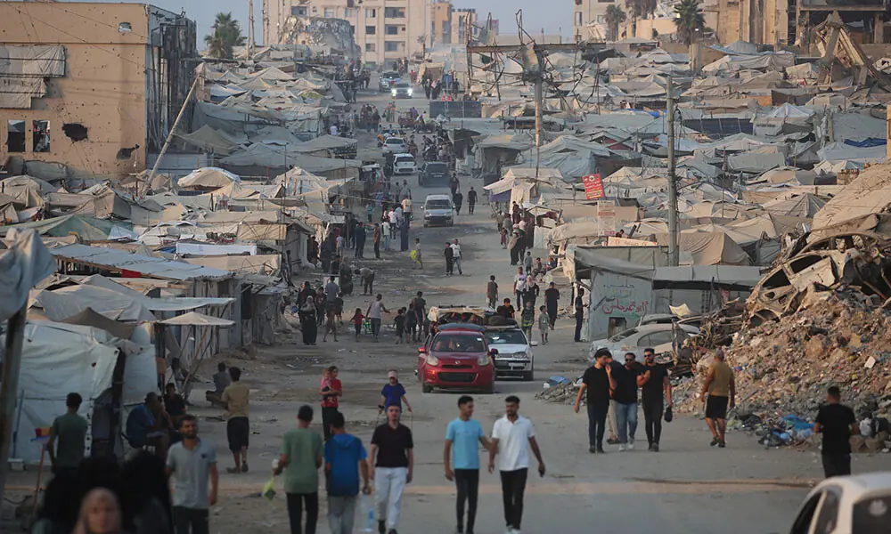 Displaced Palestinians walk past tents and destroyed buildings near the beach front in Gaza City on August 14, 2026. Photo: AFP