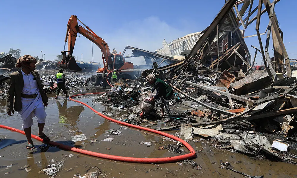Yemeni men assess the damage as emergency personnel extinguish a fire at the site of a reported overnight Saudi airstrike on a foam factory in Sanaa's Al-Rawda neighbourhood, on October 9, 2026. Photo: AFP