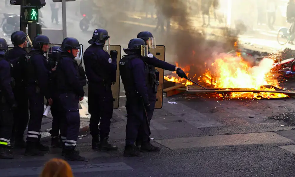 Police officers in riot gear stand near burning fire, in Paris, France, October 18, 2026. REUTERS